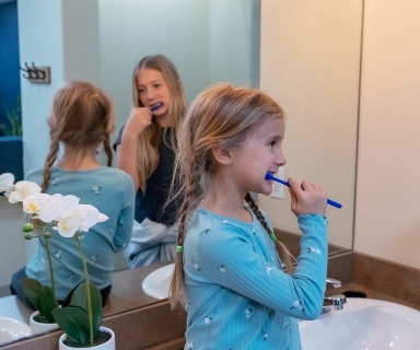 Two young girls brushing their teeth together