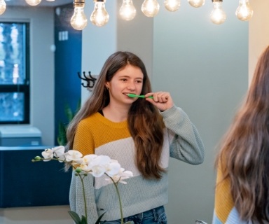 Young girl brushing her teeth in a mirror