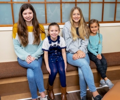 Four smiling children sitting on bench