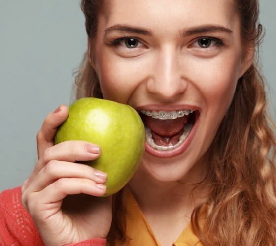 Girl with braces in Western Massachusetts holding a green apple