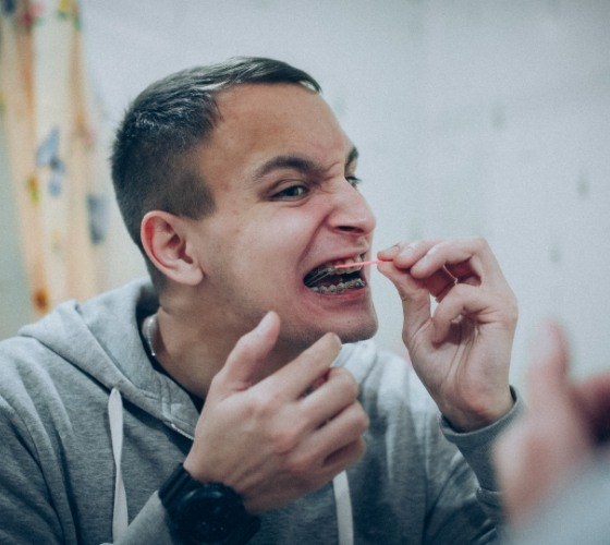 Young man with braces cleaning his teeth