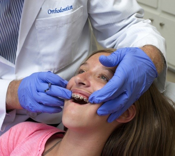 Orthodontist performing an exam on a young girl with braces