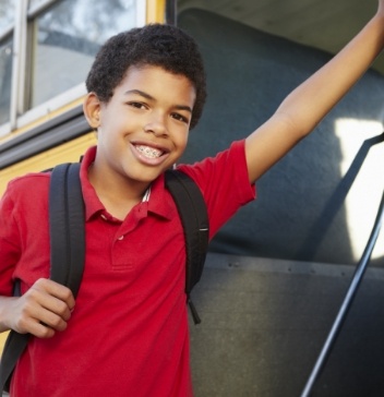 Smiling boy leaning against threshold of school bus door