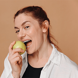 Woman preparing to bite into an apple with braces