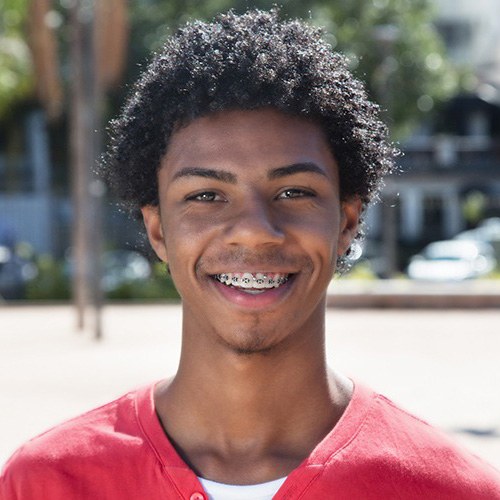 Young person smiling with braces after learning how to prevent orthodontic emergencies in Western Massachusetts