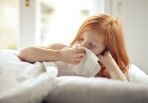 Young girl blowing her nose in a tissue