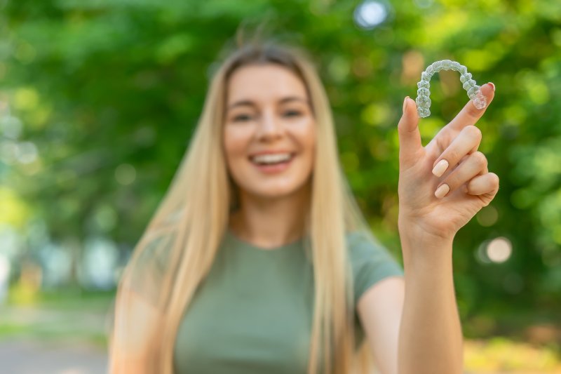 young woman outside holding Invisalign aligner