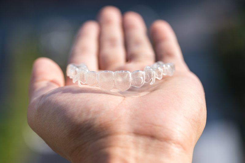 a hand holding a clear aligner