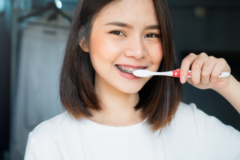 woman brushing her teeth and metal braces