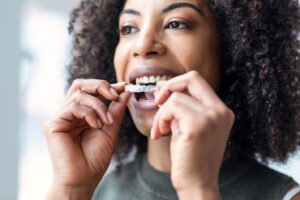 woman inserting Invisalign aligner