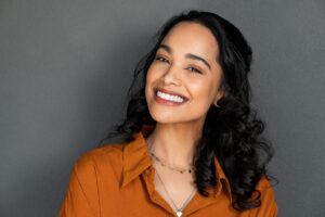 Woman in an orange blouse smiling with straighter teeth